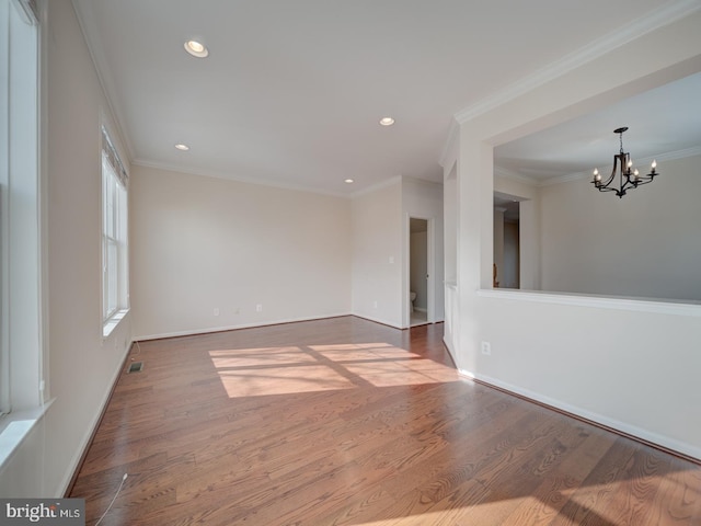 spare room featuring hardwood / wood-style flooring, crown molding, and a chandelier