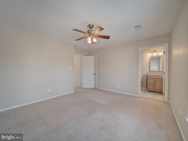 unfurnished bedroom with ceiling fan, sink, light colored carpet, and ensuite bath