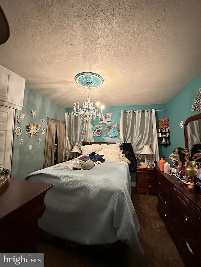 carpeted bedroom featuring an inviting chandelier and a textured ceiling