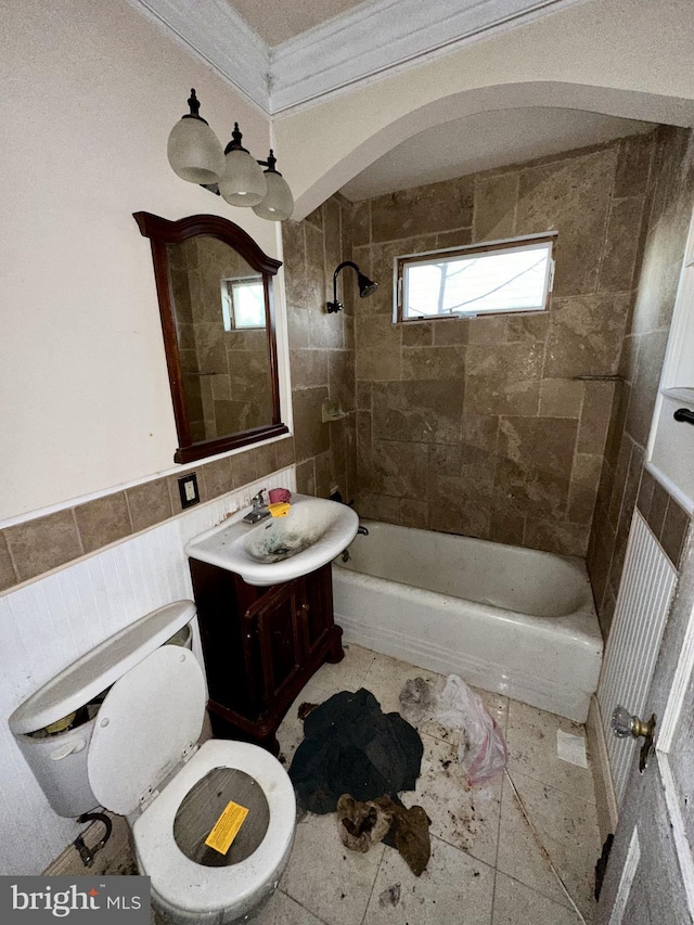 full bathroom with crown molding, tile patterned floors, tiled shower / bath combo, toilet, and vanity