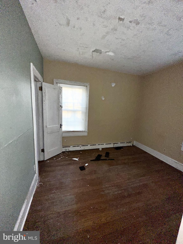 empty room with a baseboard heating unit and dark hardwood / wood-style flooring