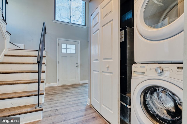 laundry area with light hardwood / wood-style floors and stacked washer and dryer