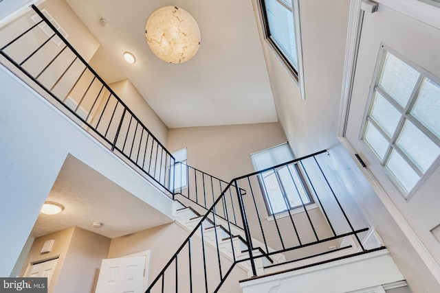 staircase with a high ceiling and a textured ceiling