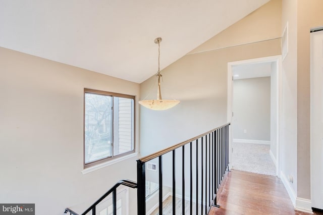 corridor with hardwood / wood-style floors and vaulted ceiling