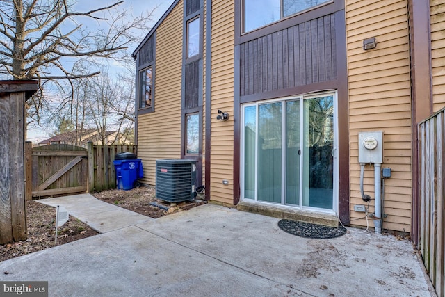 view of exterior entry with a patio and central air condition unit