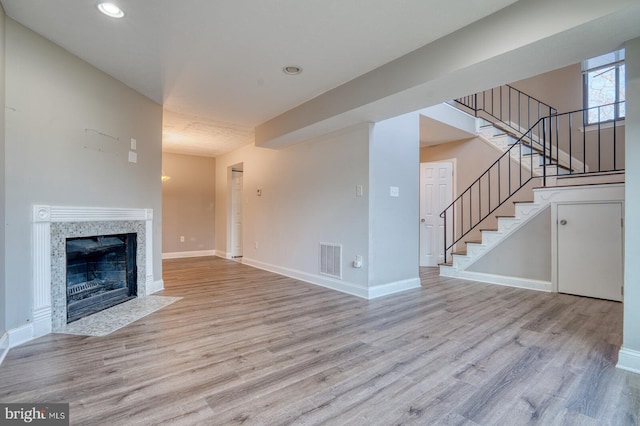 unfurnished living room with a premium fireplace and light hardwood / wood-style floors