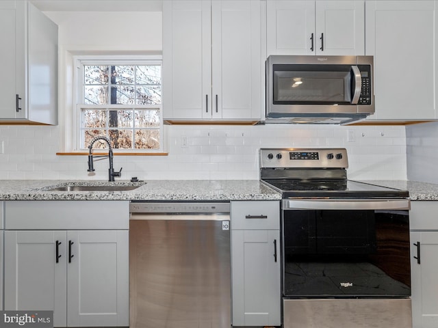 kitchen with white cabinetry, sink, light stone countertops, and appliances with stainless steel finishes