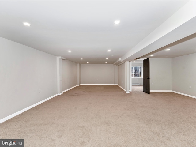 basement featuring light colored carpet and baseboard heating