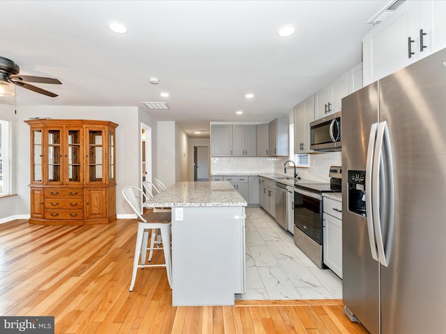 kitchen featuring sink, tasteful backsplash, a center island, a kitchen breakfast bar, and stainless steel appliances