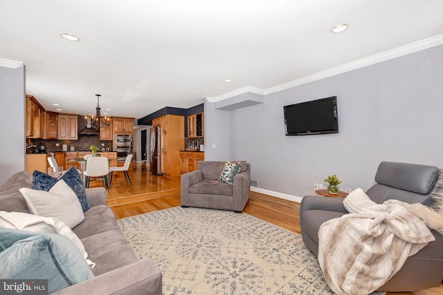 living room with a notable chandelier, light hardwood / wood-style flooring, and ornamental molding