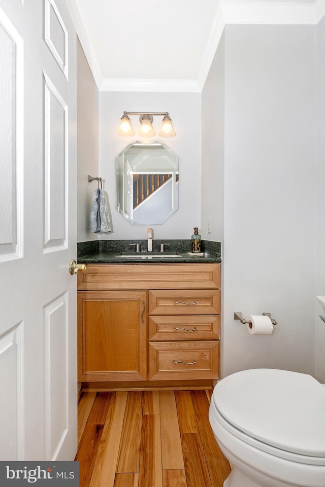 bathroom with hardwood / wood-style floors, toilet, vanity, and ornamental molding