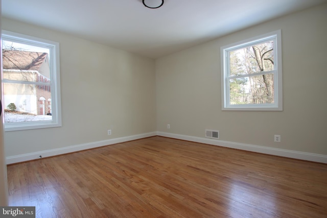 unfurnished room featuring baseboards, visible vents, and light wood finished floors