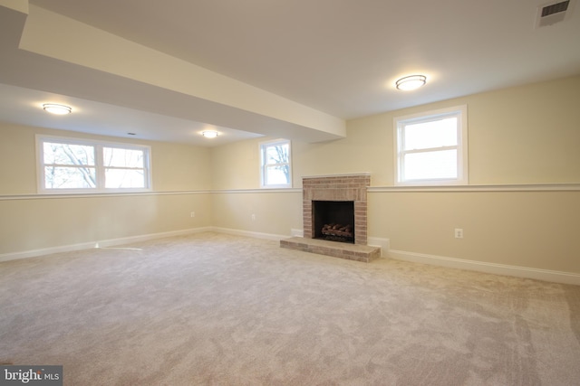 unfurnished living room with light carpet, baseboards, a fireplace, and visible vents