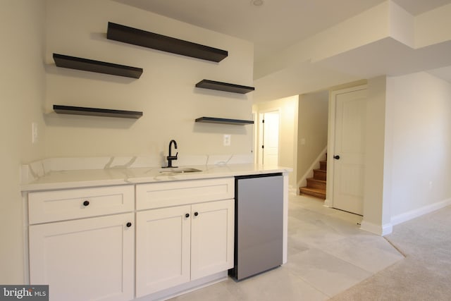 bar with stairs, a sink, freestanding refrigerator, and baseboards