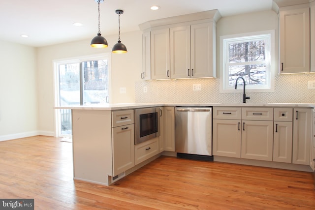 kitchen featuring light countertops, hanging light fixtures, white cabinetry, built in microwave, and dishwasher