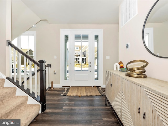 entryway featuring dark wood-style floors, visible vents, vaulted ceiling, baseboards, and stairs