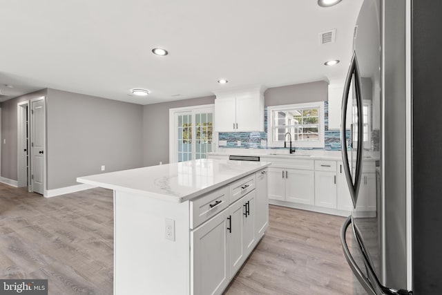 kitchen featuring plenty of natural light, visible vents, freestanding refrigerator, and a sink