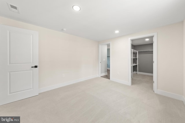 unfurnished bedroom featuring a spacious closet, visible vents, baseboards, light carpet, and recessed lighting