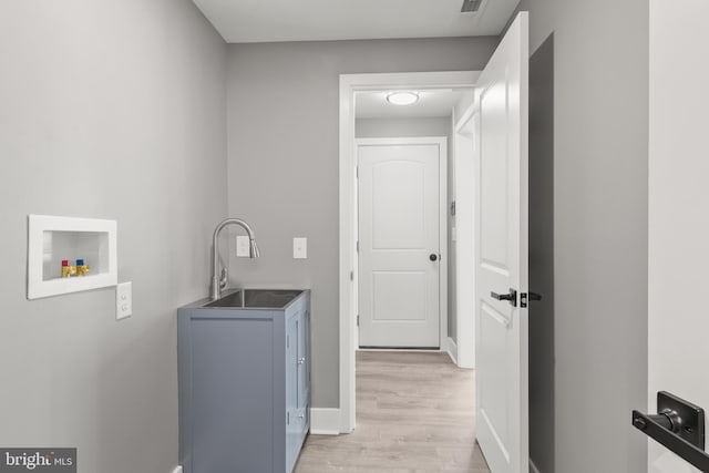 laundry room with visible vents, baseboards, light wood-style flooring, a sink, and washer hookup