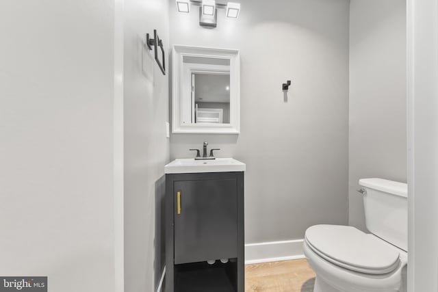 bathroom featuring vanity, toilet, wood finished floors, and baseboards