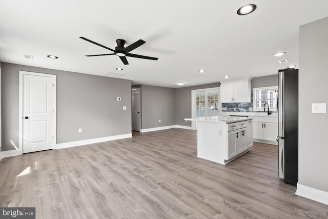 kitchen featuring light wood finished floors, white cabinets, a center island, and freestanding refrigerator