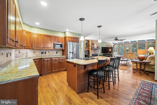 kitchen with decorative backsplash, sink, a kitchen island, light hardwood / wood-style flooring, and stainless steel appliances