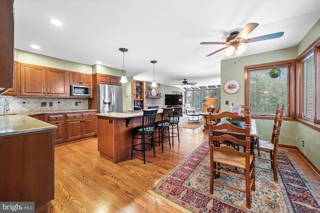 kitchen with a center island, stainless steel appliances, tasteful backsplash, a kitchen breakfast bar, and light hardwood / wood-style flooring