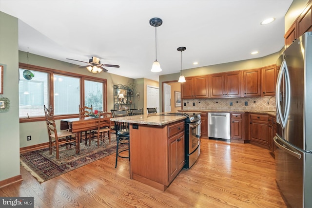 kitchen featuring pendant lighting, light stone counters, a center island, a breakfast bar, and stainless steel appliances