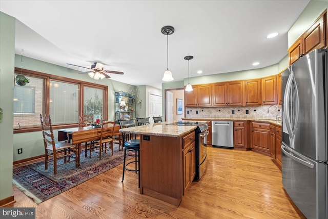 kitchen with pendant lighting, light stone counters, a breakfast bar, a kitchen island, and stainless steel appliances