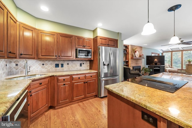 kitchen with appliances with stainless steel finishes, tasteful backsplash, sink, light wood-type flooring, and pendant lighting