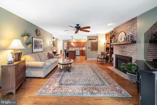 living room featuring ceiling fan, a brick fireplace, and light hardwood / wood-style floors