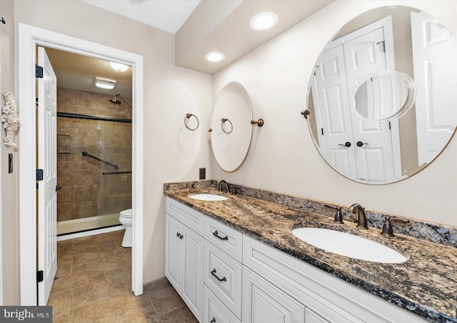 bathroom featuring a shower with door, toilet, and vanity