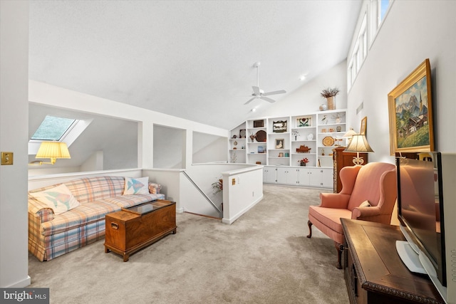 sitting room featuring a skylight, high vaulted ceiling, ceiling fan, and light carpet