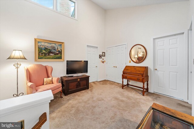 living area with a high ceiling and light colored carpet