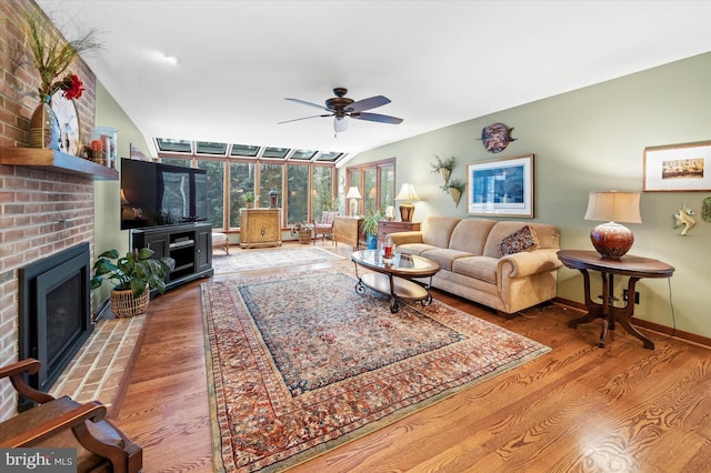 living room with ceiling fan, a brick fireplace, hardwood / wood-style floors, and vaulted ceiling