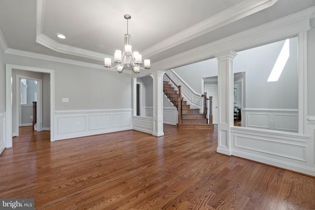 unfurnished dining area featuring crown molding, decorative columns, a raised ceiling, an inviting chandelier, and dark wood-type flooring