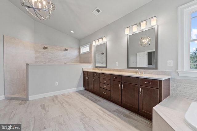 bathroom with a tile shower, vanity, lofted ceiling, and an inviting chandelier