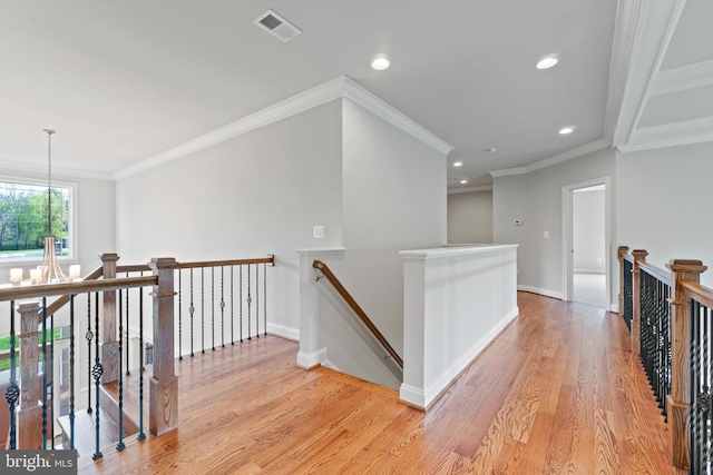 hall featuring light wood-type flooring, ornamental molding, and an inviting chandelier