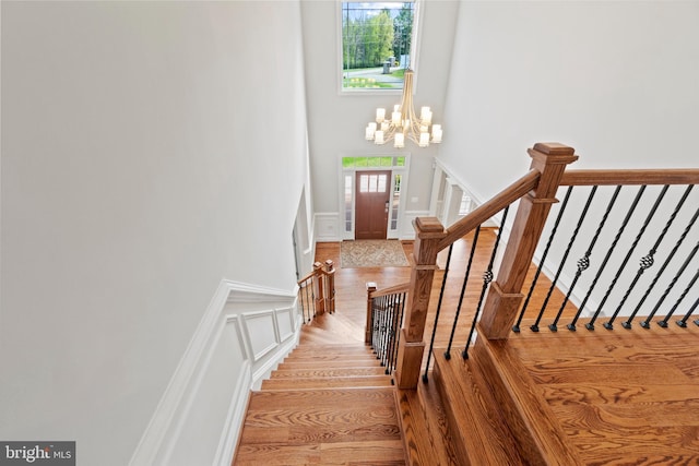 staircase with hardwood / wood-style floors and an inviting chandelier