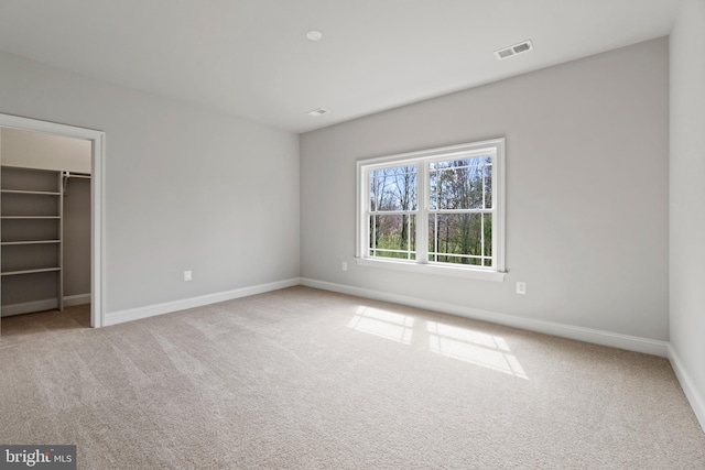 unfurnished bedroom with a spacious closet, light colored carpet, and a closet