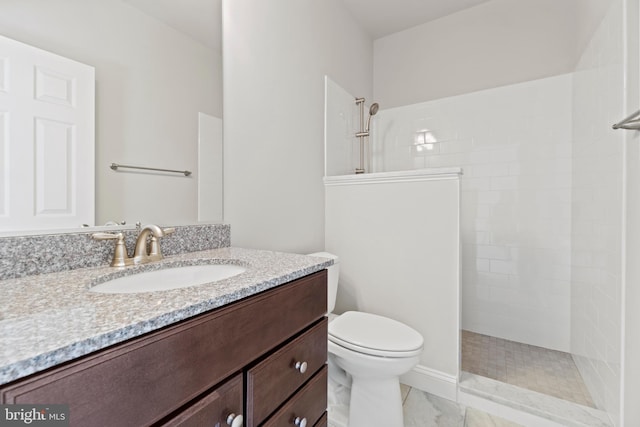 bathroom featuring tiled shower, toilet, and vanity