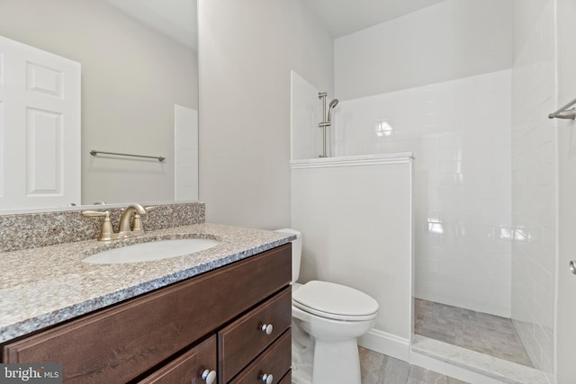 bathroom with toilet, vanity, and a tile shower