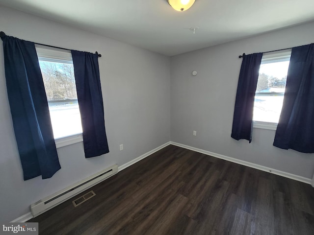 spare room with baseboard heating and dark hardwood / wood-style flooring