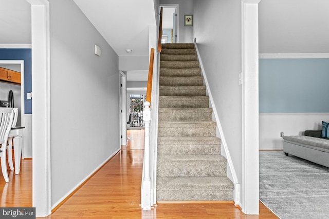 stairway with hardwood / wood-style flooring and ornamental molding