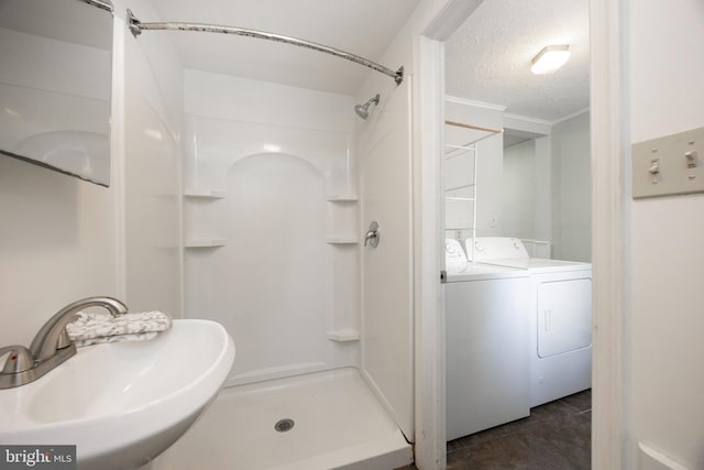 bathroom featuring sink, a textured ceiling, washer and clothes dryer, and walk in shower