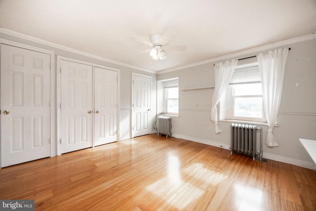 unfurnished bedroom with crown molding, radiator heating unit, and multiple closets