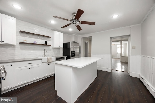 kitchen featuring a kitchen island, appliances with stainless steel finishes, white cabinetry, sink, and baseboard heating