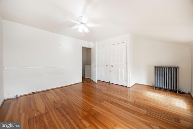 additional living space featuring wood-type flooring, radiator heating unit, and ceiling fan