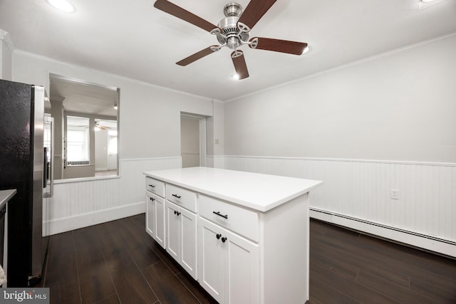 kitchen featuring dark wood-type flooring, stainless steel fridge, white cabinetry, a center island, and ornamental molding