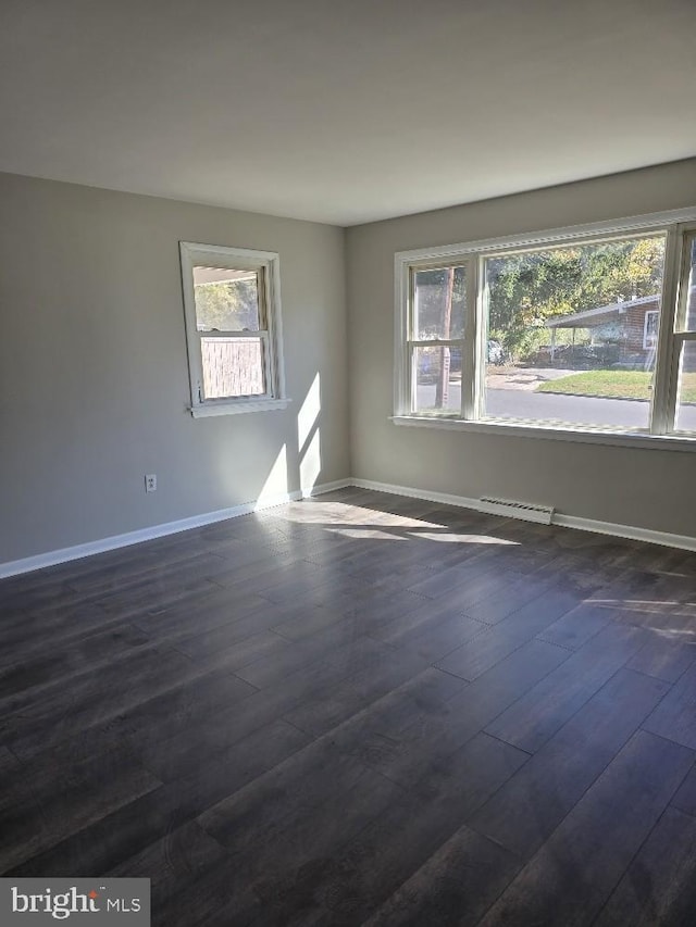 unfurnished room featuring a wealth of natural light and dark hardwood / wood-style floors